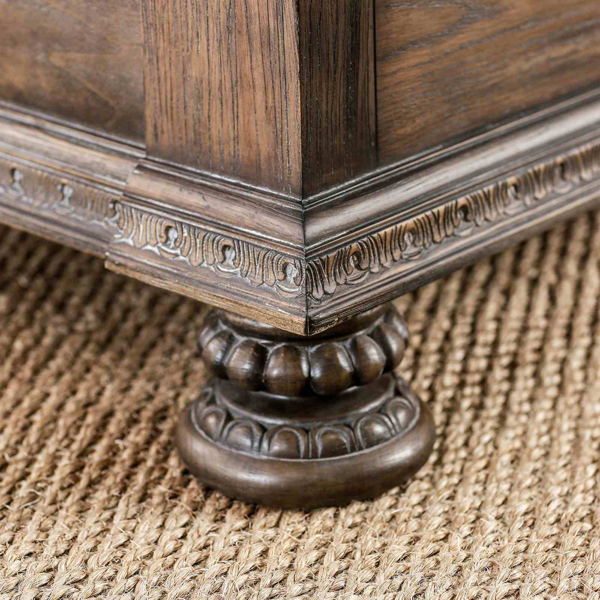 Lysandra Rustic bed footboard detail, curved beige upholstery with carved wood scroll end