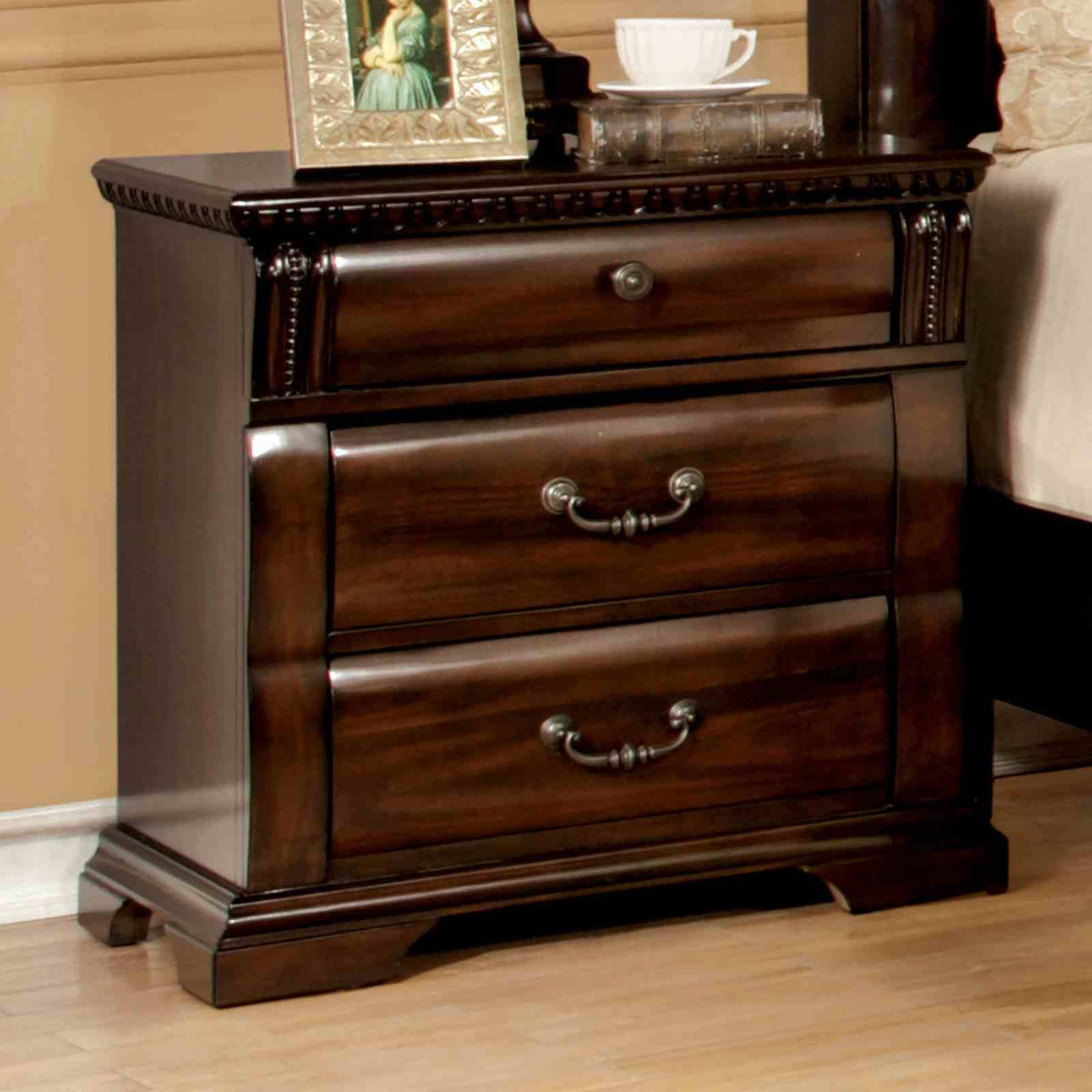 Burleigh Cherry Nightstand, three drawers with ornate pulls, angled bedroom view